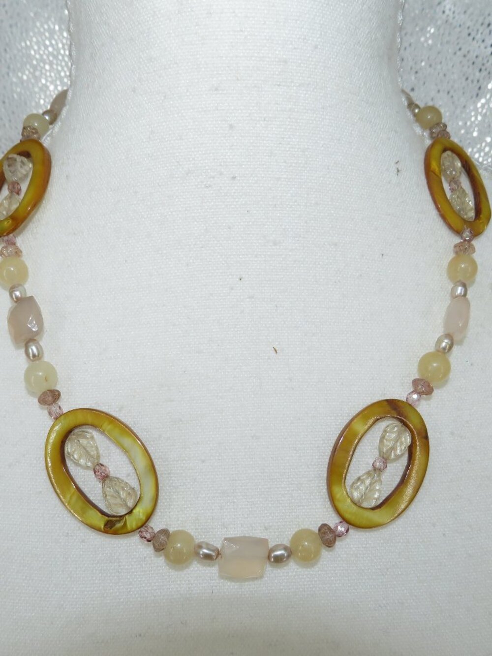 This vintage‑style neutral beaded necklace features warm honey‑brown oval center
